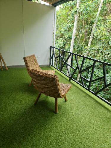 a wicker chair sitting on a balcony with green carpet at Casa Hotel Bremen in Circasia