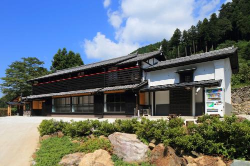a black and white building with rocks in front of it at 古民家ー芦ヶ久保 in Chichibu