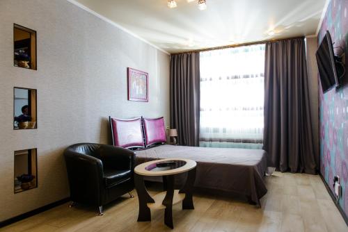 スィクティフカルにあるKosmos Apartmentsのベッドルーム1室(ベッド1台、椅子、テーブル付)
