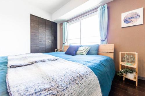 a bedroom with a bed with a blue comforter and a window at SWEET in Sapporo