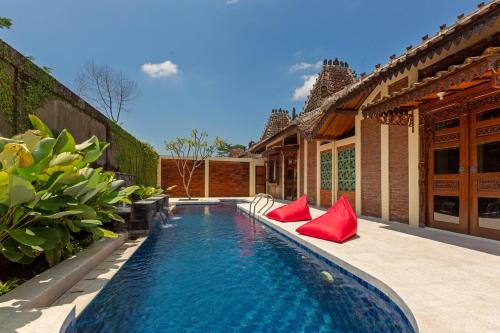a swimming pool with red pillows next to a house at Bale Devata Resort in Sleman