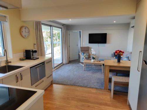 uma cozinha e sala de estar com uma mesa e um relógio em Fully Renovated Hillside Apartment Close To City em Christchurch