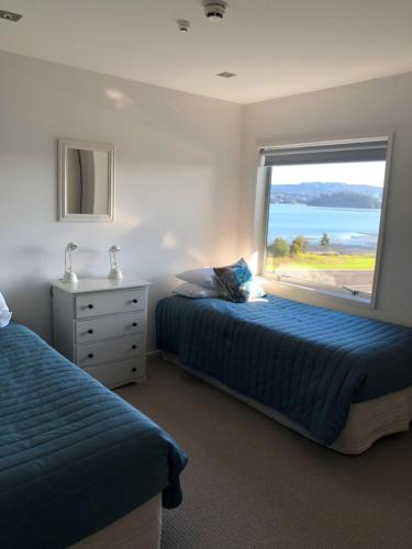 a bedroom with two beds and a large window at Ohope Beach Resort in Ohope Beach