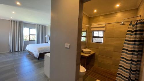 a bedroom with a bed and a bathroom with a shower at The Vaal Guesthouse in Oranjeville