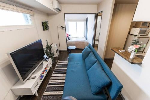 a living room with a blue couch and a television at SPARKLE in Sapporo