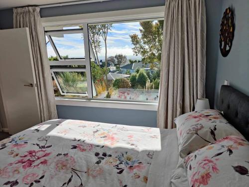 um quarto com uma cama e uma grande janela em Fully Renovated Hillside Apartment Close To City em Christchurch