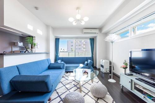 a living room with a blue couch and a tv at STARDUST in Sapporo
