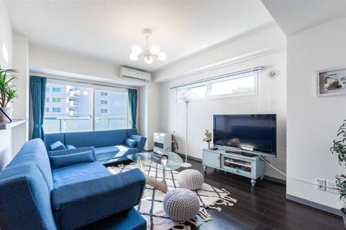 a living room with a blue couch and a tv at STARDUST in Sapporo