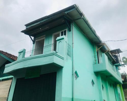 uma casa azul com uma varanda em TURU Homestay Syariah em Banjarnegara