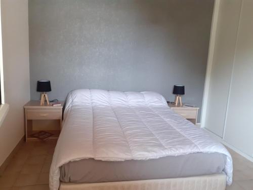 um quarto com uma cama branca com duas mesas de cabeceira em Maison vacances d'Oléron em La Brée-les-Bains