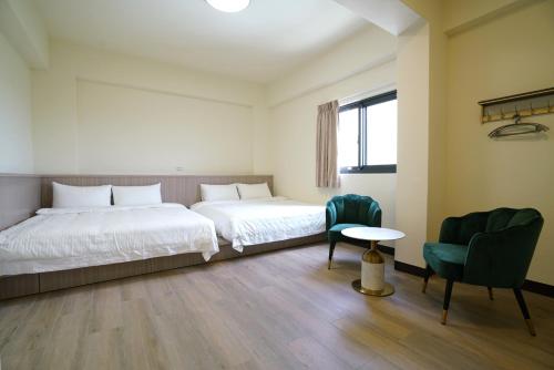 um quarto com 2 camas, uma mesa e cadeiras em 享悅二館電梯民宿 em Magong