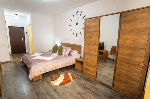 Un dormitorio con una cama y un reloj en la pared. en Seasons Primab Studio, en Brasov