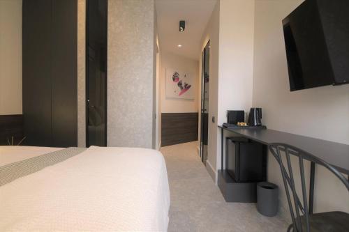 ein Hotelzimmer mit einem Bett und einem Schreibtisch mit einem TV in der Unterkunft Cityzoe Athens Suites in Athen