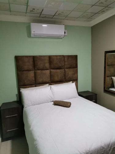 a bedroom with a large white bed with a brown headboard at Sunset View Palace Guest House in Soshanguve