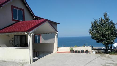 dom z czerwonym dachem z oceanem w tle w obiekcie Guesthaus Levent w mieście Trabzon