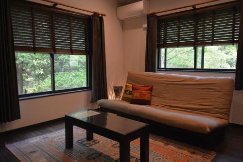 a living room with a couch and two windows at Hakone Mori No Yado in Hakone