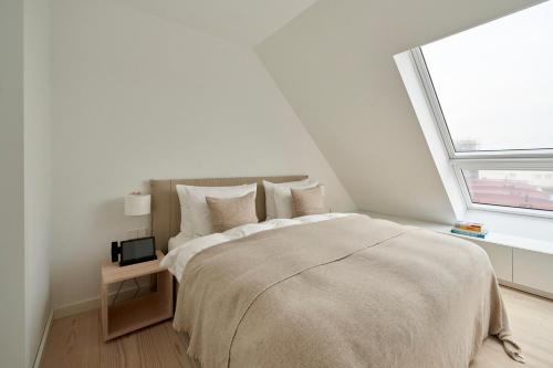 a white bedroom with a large bed and a window at Inselhouse in Norderney