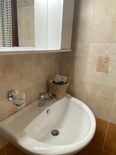 a bathroom sink with a cabinet and a basket on it at Amelia Beach Apartments in Agios Ioannis Pelio