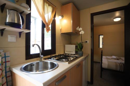 a kitchen with a sink and a stove at Camping Italia90 Caravan&Bungalow in Domaso