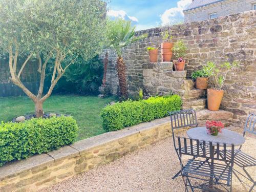 a table and chairs in a garden with a stone wall at Maison de caractère datant de 1739 in Quistinic