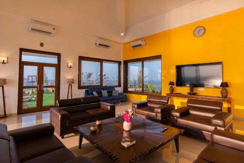 a living room with leather furniture and a flat screen tv at StayVista at Sunset on the Lake - Infinity Lakeview Swimming Pool with Contemporary Interiors & Lavish Amenities in Igatpuri