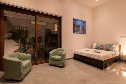 a bedroom with a bed and two chairs at StayVista at Sunset on the Lake - Infinity Lakeview Swimming Pool with Contemporary Interiors & Lavish Amenities in Igatpuri