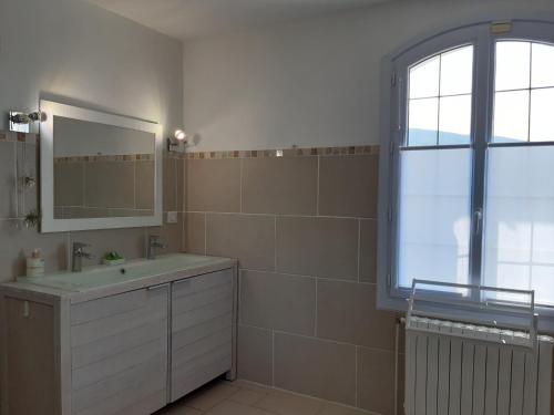une salle de bain avec un lavabo, un miroir et une fenêtre dans l'établissement Villa l'Edenca, à Auriol