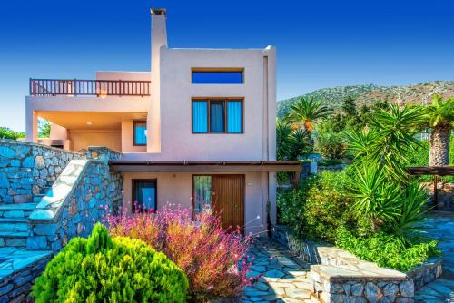 a house with a stone wall and palm trees at Ida Village I & II in Hersonissos