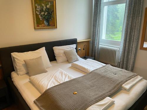 a bed with white sheets and pillows and a window at Villa Clar im Park in Bad Gleichenberg