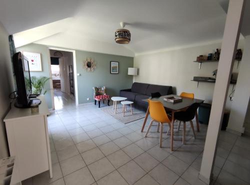 ein Wohnzimmer mit einem Sofa, einem Tisch und Stühlen in der Unterkunft Gîte La p'tite terrasse Chinon centre in Chinon