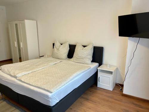 a bedroom with a bed with white sheets and a flat screen tv at Appartement im Zentrum von Baienfurt in Baienfurt