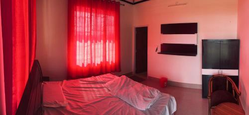 a bedroom with red curtains and a bed at Kanva Farms in Kotdwāra