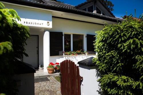 a house with a fence and flowers in front of it at Apartamenty Poddąbie1 in Poddąbie