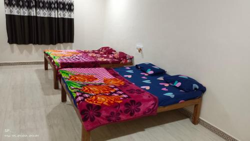 two beds in a room with colorful sheets on them at The Royal Ascot Holiday Home in Alibaug