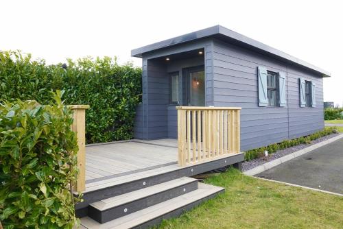 una pequeña casa azul con terraza de madera en Clonlum Holiday Cottages, en Newry