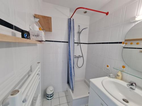 uma casa de banho branca com um chuveiro e um lavatório. em REF 035 - Belle maison en pierre pour quatre personnes proche Golfe du Morbihan ARZON em Arzon