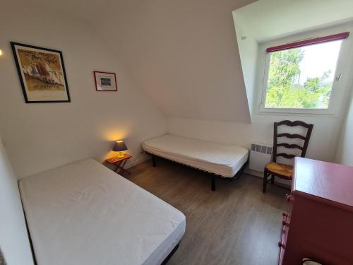 une petite chambre avec deux lits et une fenêtre dans l'établissement REF 035 - Belle maison en pierre pour quatre personnes proche Golfe du Morbihan ARZON, à Arzon