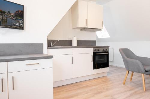 a kitchen with white cabinets and a sink and a chair at Landschaftliches Haus in Tönning