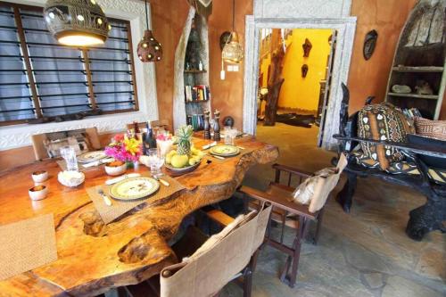 a dining room with a wooden table with food on it at Villa Ndoto in Diani Beach