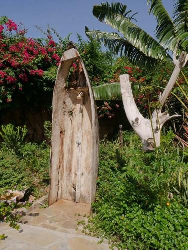 a wooden door with a cow statue in a garden at Villa Ndoto in Diani Beach