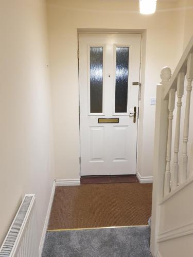 a hallway with a white door and stairs at Cheerful 4 Bedroom Townhouse with free parking in Kenton