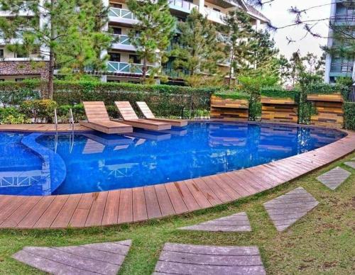 a swimming pool with benches at StayPlus Tagaytay London Suite 50MBPS WIFI+parking in Tagaytay