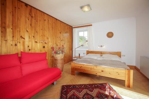 a living room with a red couch and a bed at Gästehaus Schreier in Ledenitzen