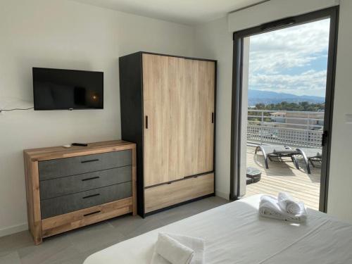 - une chambre avec un lit, une télévision et une porte coulissante en verre dans l'établissement BLUE AGOSTA, à Grosseto-Prugna