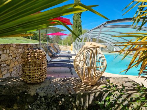 deux vases assis sur un mur à côté d'une piscine dans l'établissement Les Chenes Rouges, à Veyrines-de-Domme