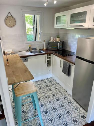 La cuisine est équipée d'un réfrigérateur, d'une table et d'un évier. dans l'établissement Cottage Les Palmiers, à Houlgate