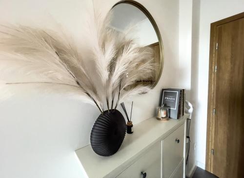 a black vase with feathers on a wall with a mirror at HARMONY Apartment - Zator Energylandia in Zator