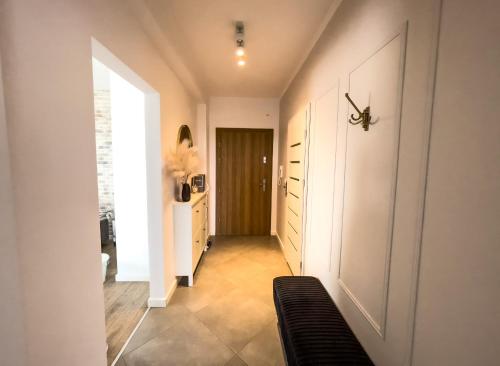 a hallway with white walls and a door with a black couch at HARMONY Apartment - Zator Energylandia in Zator