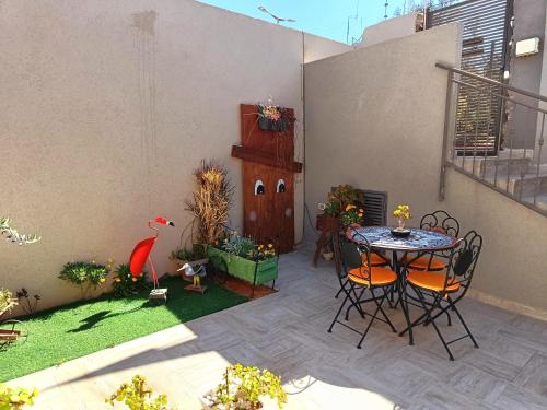 un patio con mesa y sillas y un jardín en רקפת - יחידה במדבר, en Arad