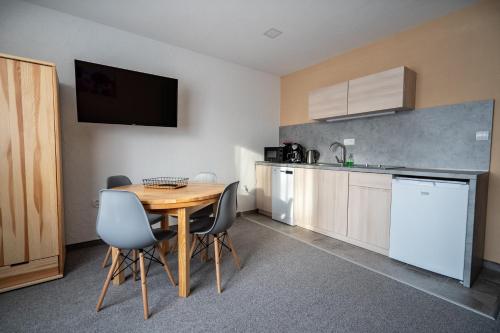 a kitchen with a table and chairs and a kitchen with a television at Apartmány Janka + camp in Bešeňová